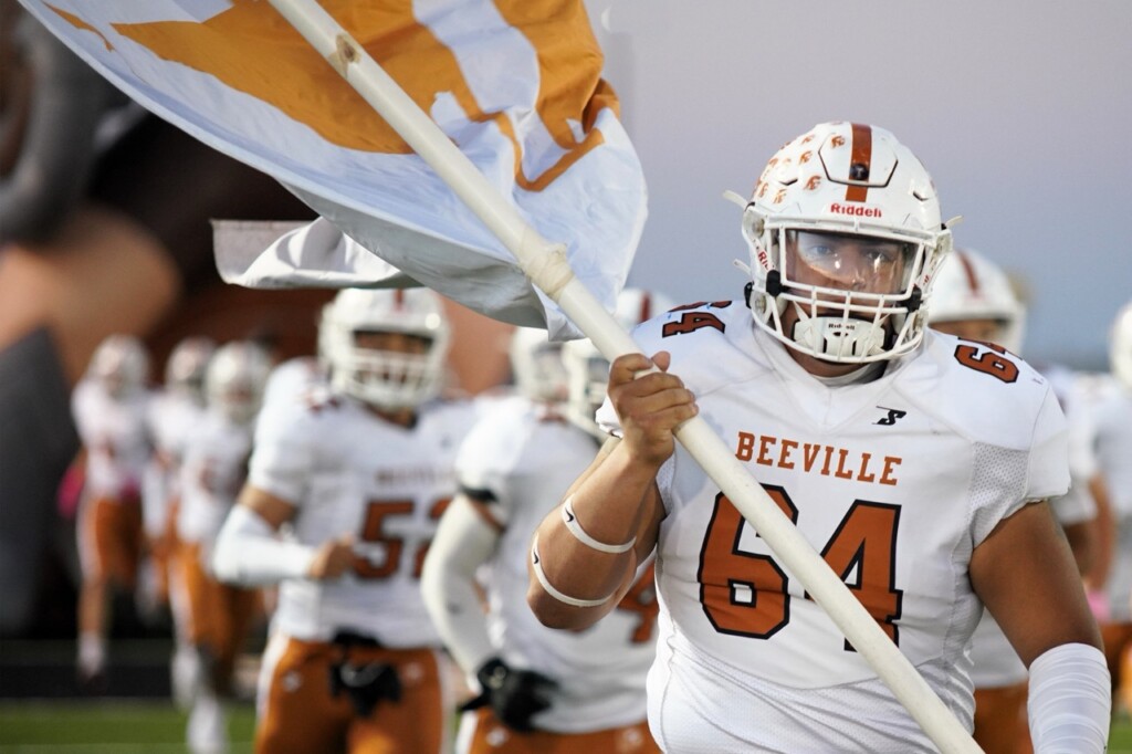 beeville isd trojan football team takes the field, #64 carries the team flag
