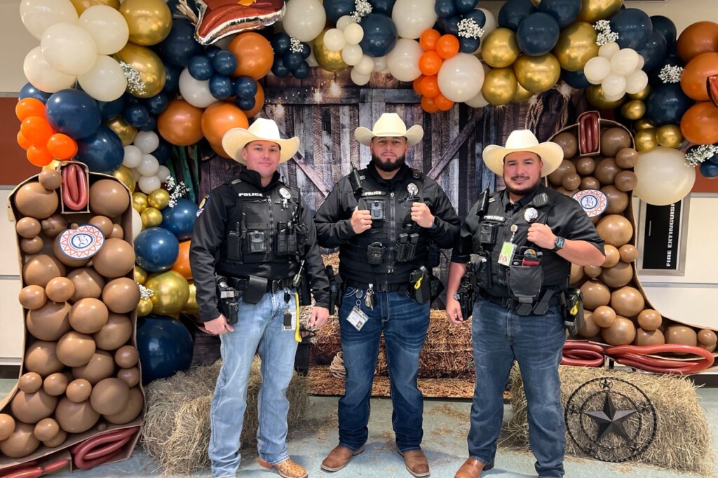 three security resource officers in full uniform pose in front of a balloon arch